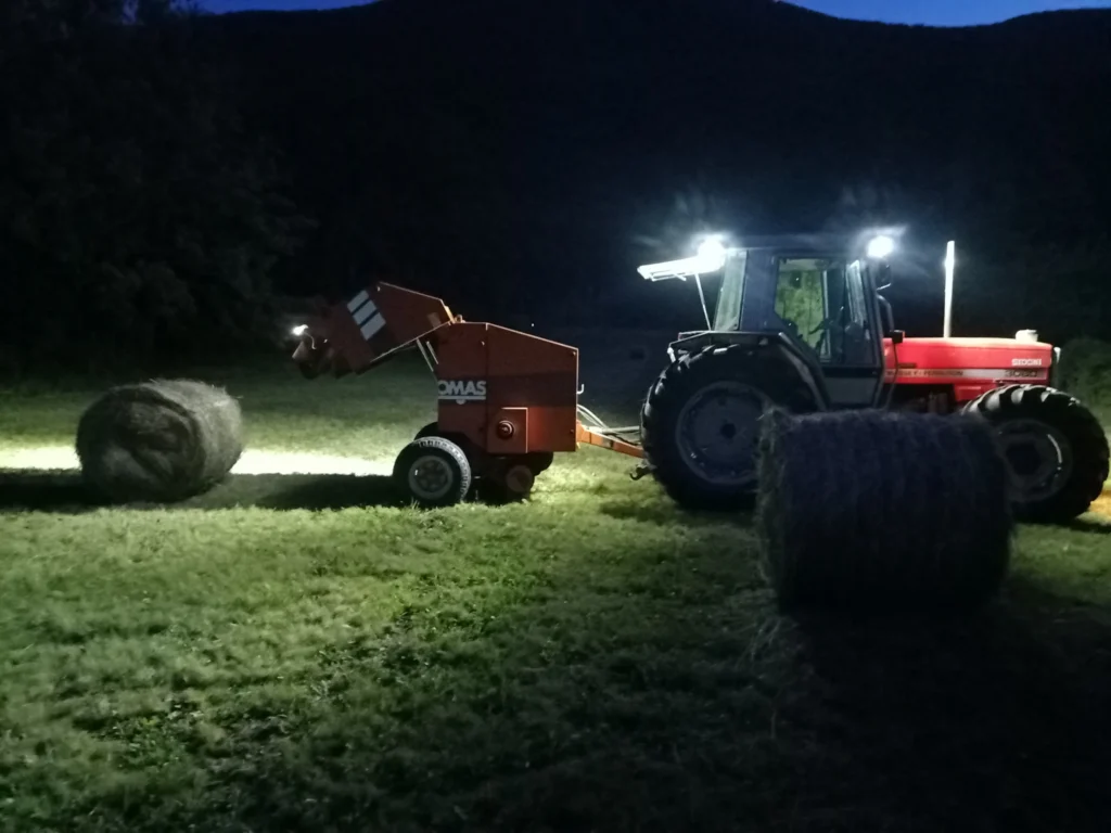 Trattore e rotopressa in un campo di notte
