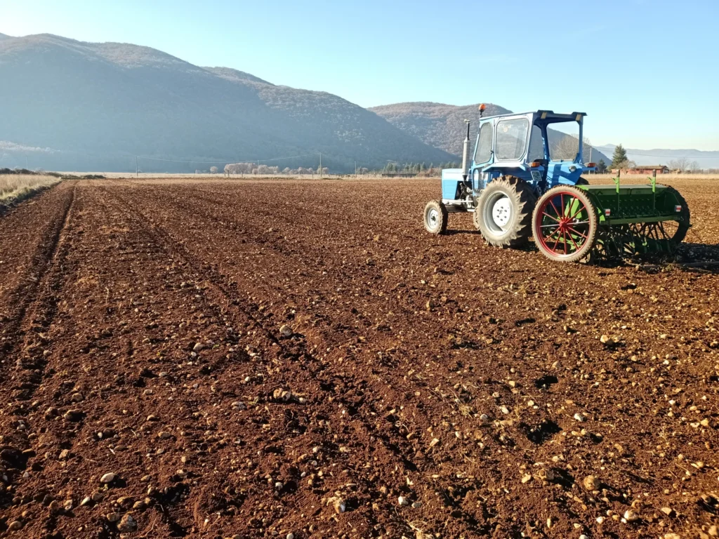 Trattore su un campo arato con montagne sullo sfondo