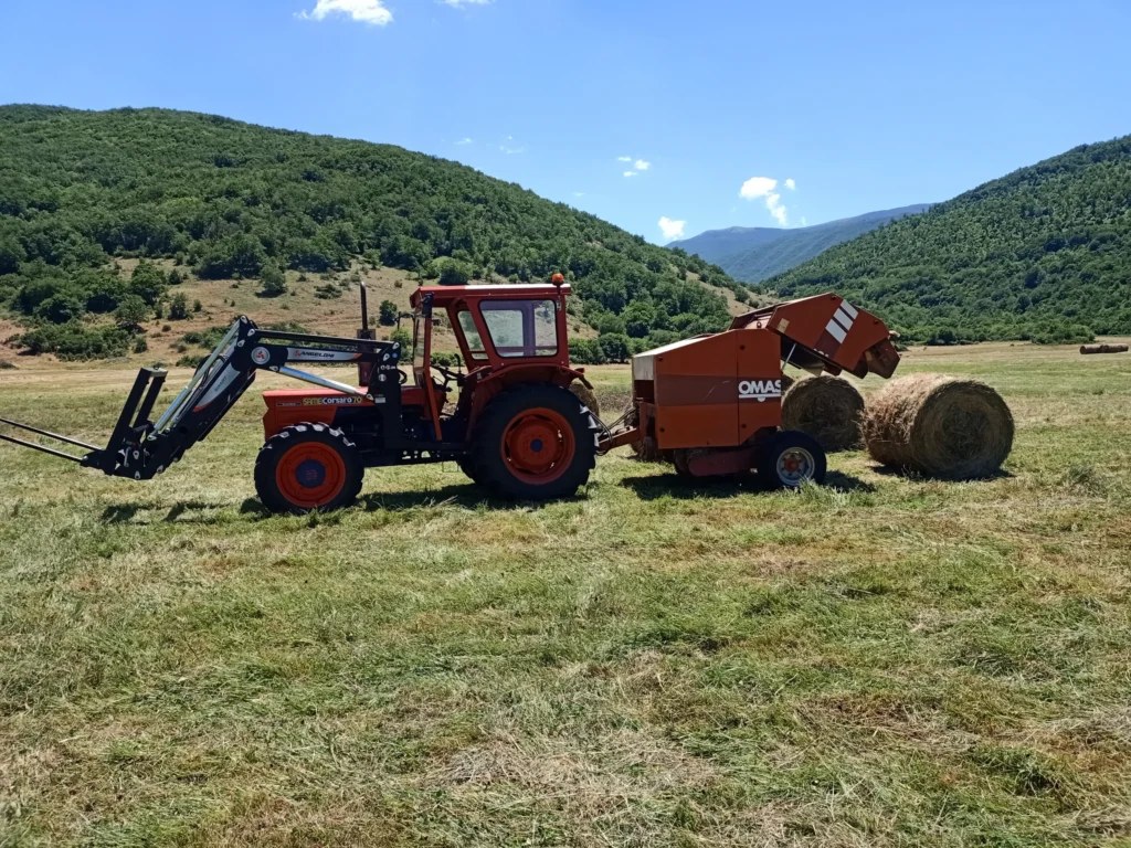 Trattore con rotopressa e balla di fieno in un campo